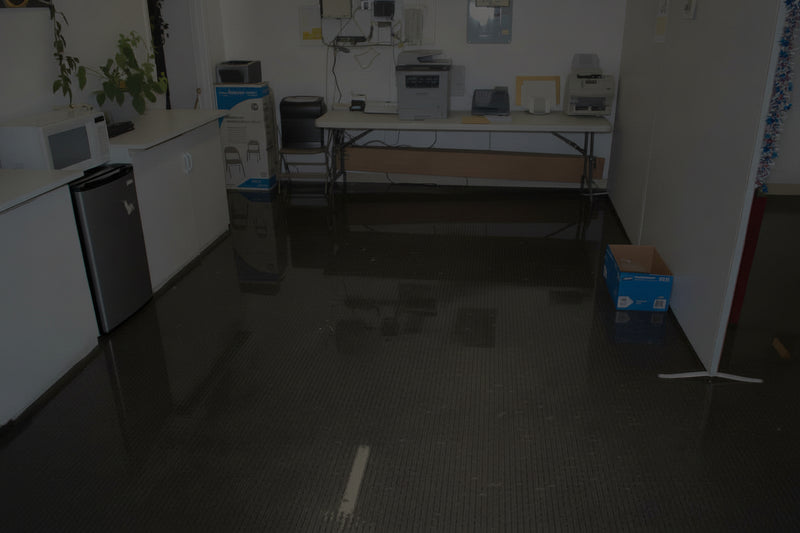 Flooded room with water covering the floor, appliances, and furniture partially submerged.