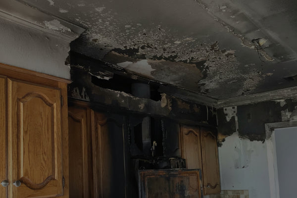Kitchen with fire damage showing charred ceiling and cabinets