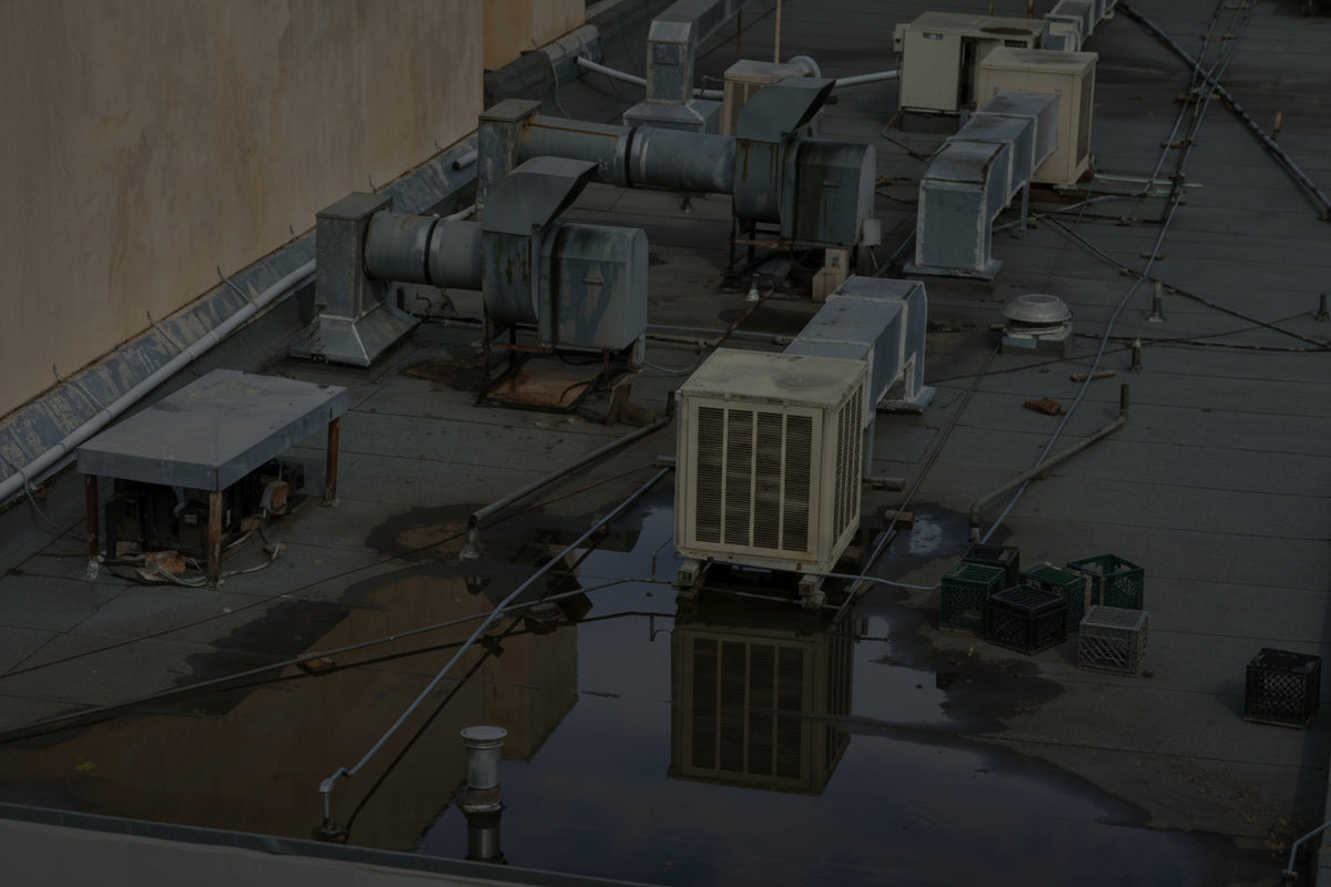 Roof with HVAC systems and water pooling on a building.